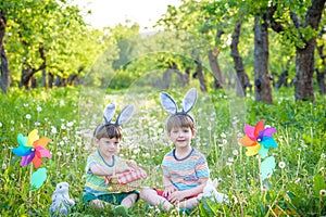 Two cheerful boys sit on the lawn after Easter eggs hunt