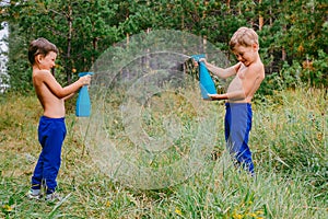 Two cheerful boys splashing water in the summer heat