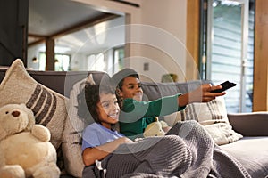 Two cheerful boys watching TV using remote control