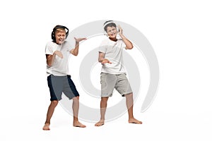 Two cheerful brothers listening music in headphones and dancing