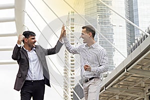 Two cheerful business men clapping each other hands and smiling.