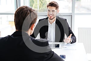 Two cheerful businessmen using tablet and working on business meeting