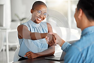Two cheerful businesspeople shaking hands in a interview together at work. Happy colleagues greeting with a handshake in