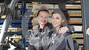 Two cheerful female factory workers hugging smiling happily to the camera