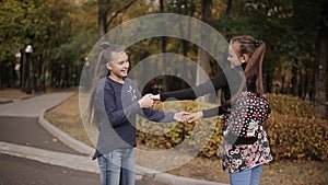 Two cheerful friends ride and dance on an electronic scooter in an autumn park.