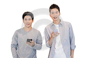 Two cheerful friends wear gray t-shirts standing isolated over white background, holding mobile phone.Couple of cool guys using
