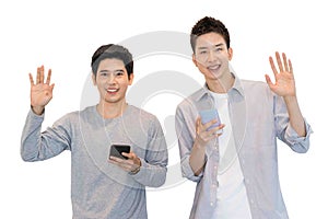 Two cheerful friends wear gray t-shirts standing isolated over white background, holding mobile phone.Couple of cool guys using