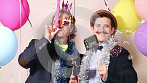 Two cheerful guys holding sign in love in photo booth