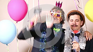 Two cheerful guys holding sign in love in photo booth