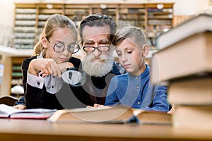 Two cheerful happy kids, boy and girl with magnifying glass glass listening to interesting book story from their