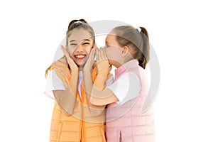 Two cheerful little girls share secrets in each other s ear.