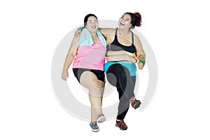 Two cheerful overweight women laughing in studio