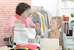 Two cheerful seamstresses working together in