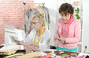 Two cheerful seamstresses working together in