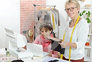 Two cheerful seamstresses working together in