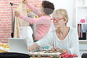 Two cheerful seamstresses working together in