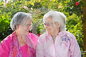Two cheerful senior women relaxing in garden