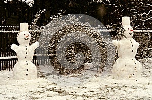 Two cheerful snowmen standing in the garden