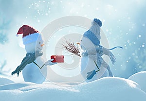 Two cheerful snowmen standing in winter christmas landscape.