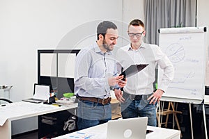 Two cheerful webdesigners standing at office