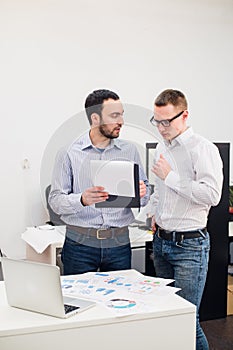 Two cheerful webdesigners standing at office