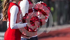 Two cheerleaders with red and white pom poms