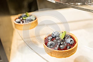 Two cheesecakes with fresh fruits on glass table