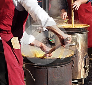 Two chef cook polenta in the traditional way of north east italy on small wood-fired cookers
