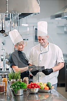 Two chefs discuss the menu in the kitchen of a restaurant or hotel.