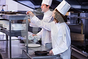 Two chefs working at order station in a kitchen