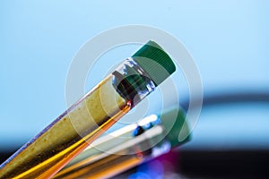 Two chemical test tubes with closed lids with orange liquid on blue background