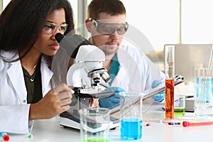 Two chemistry students conduct microscopic examinations in laboratory