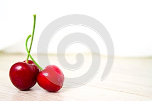 two Cherries Close-up. Cherry on wood and white background. Copyspace - healthy eating and food concept