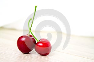 two Cherries Close-up. Cherry on wood and white background. Copyspace - healthy eating and food concept