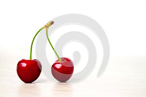 two Cherries Close-up. Cherry on wood and white background. Copyspace - healthy eating and food concept
