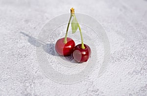 Two cherries lie on a gray background. Two ripe juicy cherries on one branch. Background with fruits