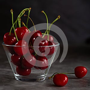 Two cherries on the table and bowl full of cherries