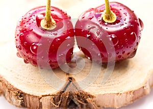 Two cherries on a wooden board