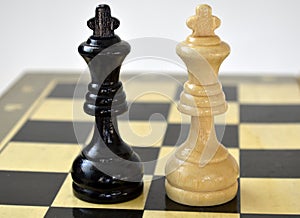 Two chess pieces of kings next to each other on the background of the chessboard