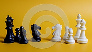 Two chess pieces, one black and one white, are on a yellow background