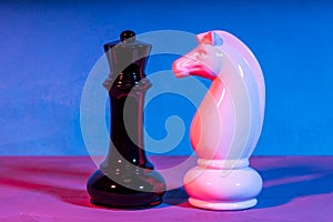 Two chess pieces white and black illuminated by different light sources