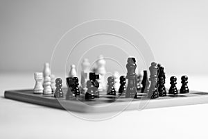 Two chess teams one in front of other on the chessboard. white background