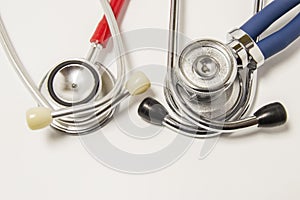 Two chestpieces of stethoscopes large diaphragm down with red and blue acoustic tubes lie on white background. Concept for cardiol