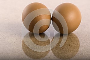 Two chicken brown eggs reflected in a wooden table