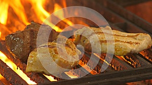 Two chicken fillets and a slice of veal or beef grilling on the grill in the background fire flames, restaurant cuisine