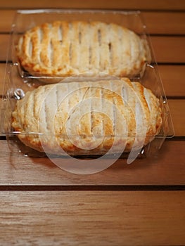 Two chicken pies in a plastic packaging, on a wooden brown table