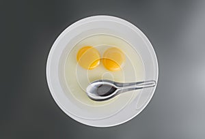 Two chicken Raw egg yolks and stainless spoon