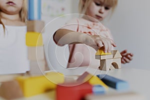 Two child girl sisters playing with colorful wooden toy building blocks