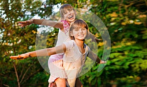 Two child girls playing together. Sisters play Superhero. Happy kids having fun, smiling and hugging. Family holiday