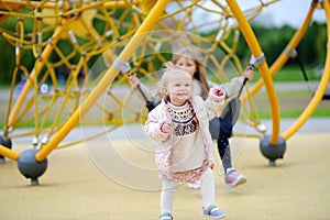 Two child having fun on outdoor playground. Spring/summer/autumn active sport leisure for kids. Outdoor activities for baby and